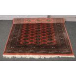 A large red ground wool rug, 222cm x 316cm. Good condition.