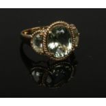 A 9ct gold three stone prasiolite dress ring set as a large ovoid stones flanked by a pair of demi