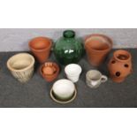 A quantity of terracotta garden planters along with a green glass carboy.