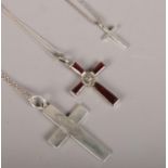 Three silver crosses on silver chains.