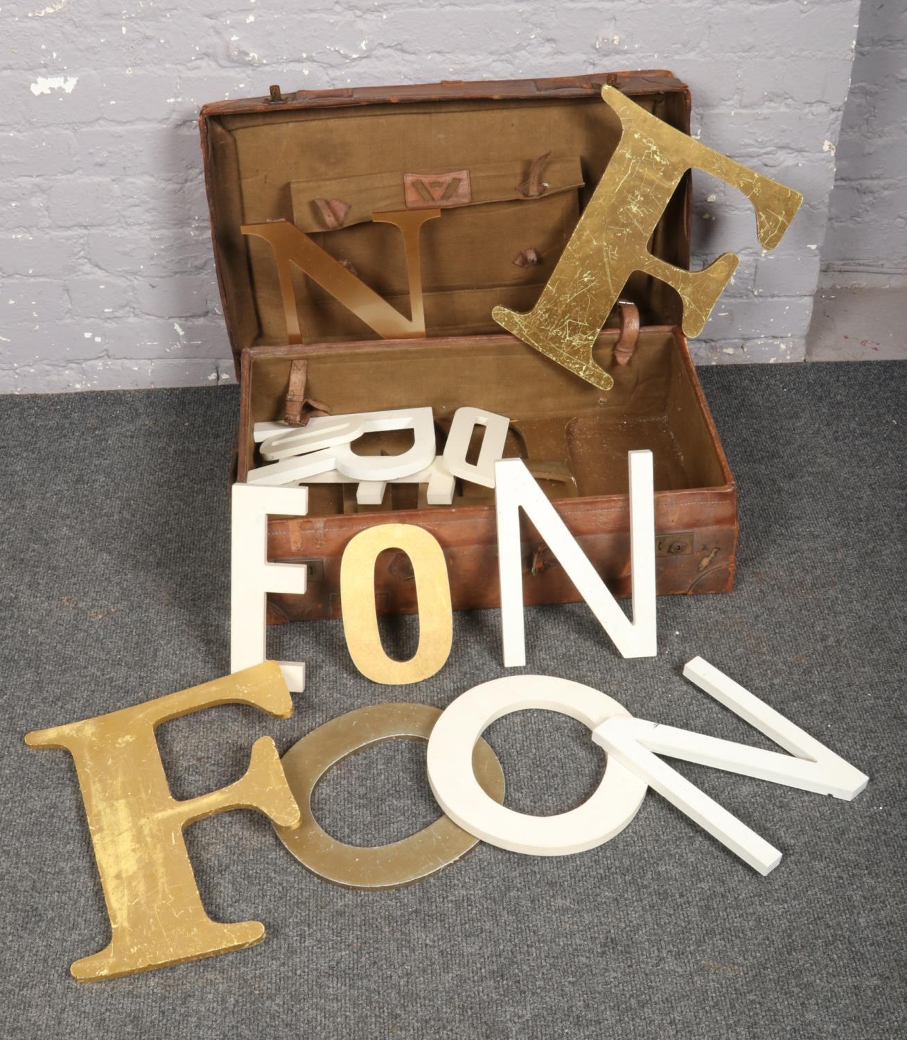 A vintage leather suitcase and contents of gilt and painted shop front sign lettering.