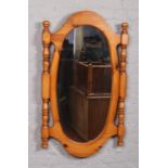 An oval hall mirror with pine frame incorporating turned side supports, 120cm x 70cm.