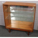 A Turnidge teak display cabinet with glass sliding doors.