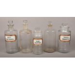 Five vintage glass chemical storage bottles, some with labels.