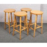 A set of four wooden bar stools raised on turned supports. One stool with damage.