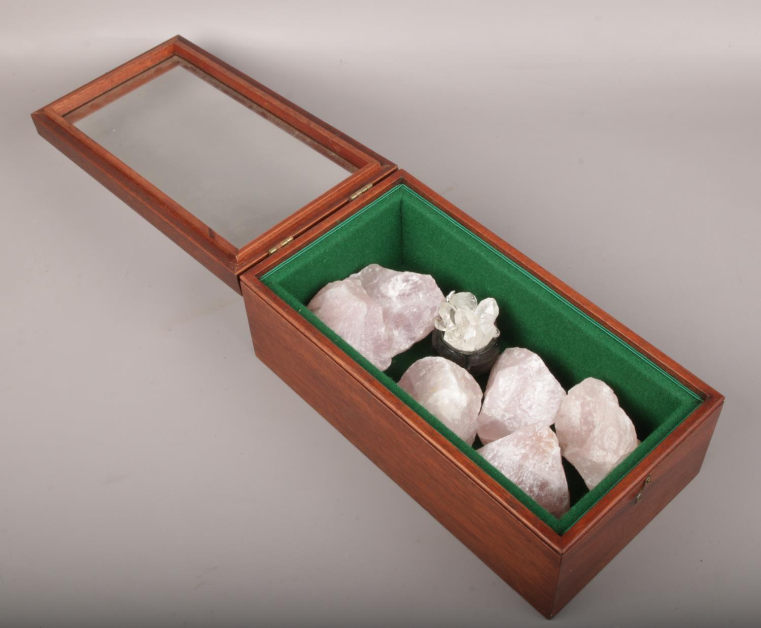 A mahogany and glass display case with contents of rose quartz crystals.