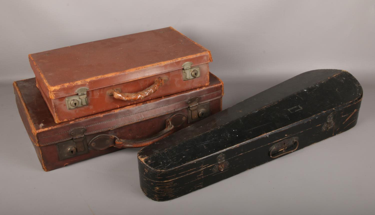 Two vintage suitcases and a wooden violin case.