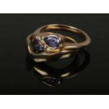 A 9ct gold tanzanite and diamond crossover ring with adjacent fitted 9ct gold band en suite, size K.