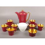 A Crown Devon Art Deco six place coffee set, claret ground and with gilt interior, along with a