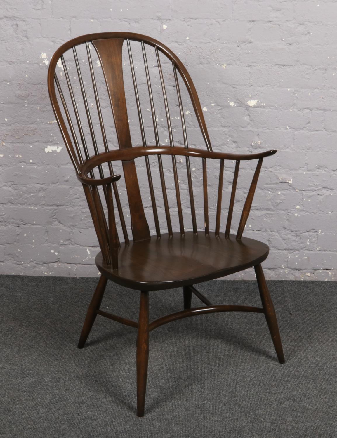 An Ercol Windsor arm chair with crinoline stretcher. Wear to one spindle. Slight wear to arm.
