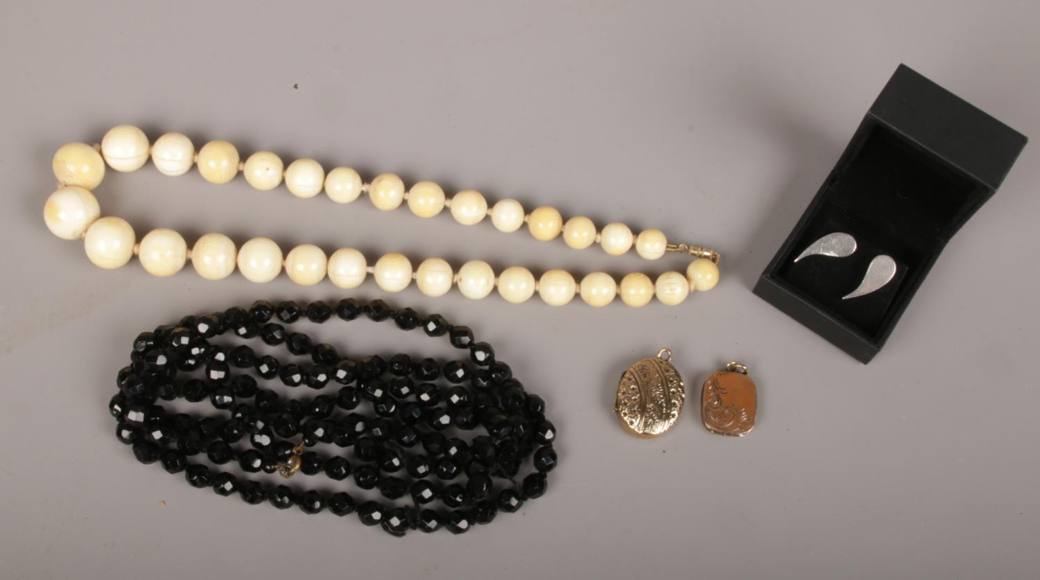 A small collection of jewellery to include two yellow metal lockets, french jet necklaces, cuff