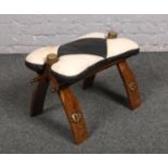 A wood and leather camel saddle stool.