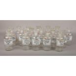 18 vintage laboratory glass chemical storage bottles and stoppers with printed labels.
