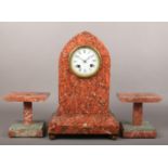 A 19th century French red and grey marble clock garniture. With enamel dial and housing an 8 day