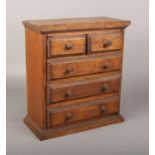 An early 20th century apprentice made oak chest of two over three drawers. With turned drawer