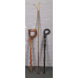 Two African carved wooden walking sticks and a thumb stick with antler terminal.