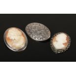 Two silver mounted carved shell cameo brooches and another silver brooch.