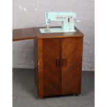 An electric Singer sewing machine in oak cabinet.