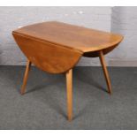 An Ercol light elm drop leaf dining table, on splay supports.