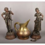 A large pair of spelter figures depicting farm workers along with an antique brass and copper jug.
