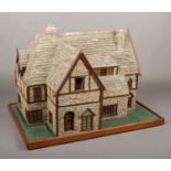 A detailed stone and wooden model of a cottage. Raised on a simple rectangular plinth and with