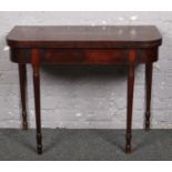 A Regency mahogany fold over card table with broad crossbanding and raised on ring turned supports.