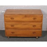 An Ercol light elm chest of three drawers. (Height 66cm Width 92cm Depth 45cm).