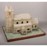 A detailed stone and wooden model of a church. Raised on a simple rectangular plinth and with