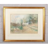 A framed watercolour, country road landscape scene with a female figure, signed indistinct. (26cm