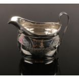 A George III silver cream jug. With reeded strap handle and engraved with festoons. Assayed London