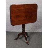 A stained pine tilt top occasional table.