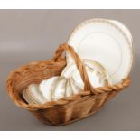 A basket containing four Royal Doulton Gold Lace trios along with a sandwich plate and milk jug.