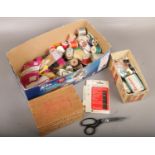 A box of sewing equipment to include needles, coloured thread, buttons, elastic etc.