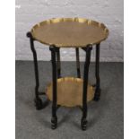 A two tier brass table, with ebonised stand and oriental scenes.