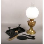 A brass oil lamp with milch glass shade, along with an ebonised dressing table set.