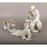 A Lladro figure of a clown laying down, along with a Nao figure group of a clown and a young boy