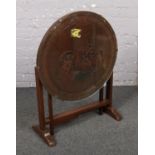 A wooden tilt top occasional table with carved oriental design.