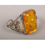 A silver bracelet with large amber effect panel.