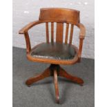 An Oak Captains swivel chair with slat back.