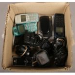 A box of old mobile phones and chargers.