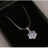 A silver tanzanite and diamond floriform pendant on snake chain.