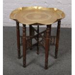 An Indian brass top table, on folding wooden base.