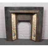 A Victorian cast iron fire surround with floral tiles.