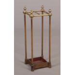 An Edwardian small brass stick stand. With turned finials and raised on an iron base, 67cm high.