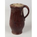 A 17th century brown glazed earthenware mug with plain strap handle, 19cm. Chipping and flakes to