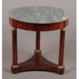 A French Empire marble top mahogany centre table of circular form. Raised on three column supports