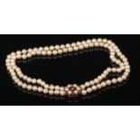 A two row cultured pearl necklace. With 9 carat gold starburst clasp set with pearls and garnets,