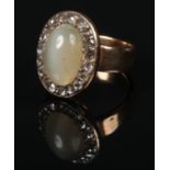 A gold ring with central ovoid cabochon green hardstone under a border of rose cut diamonds (tests