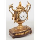 An early 19th century French Neo-Classical style gilt bronze mantel clock of urn form and raised