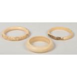 The Japanese Meiji period ivory bangles. Two with carved decoration, one with a peacock and pea hen,